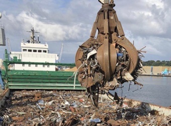 Scrap metal grabber dropping ferrous metal into a vessels container.