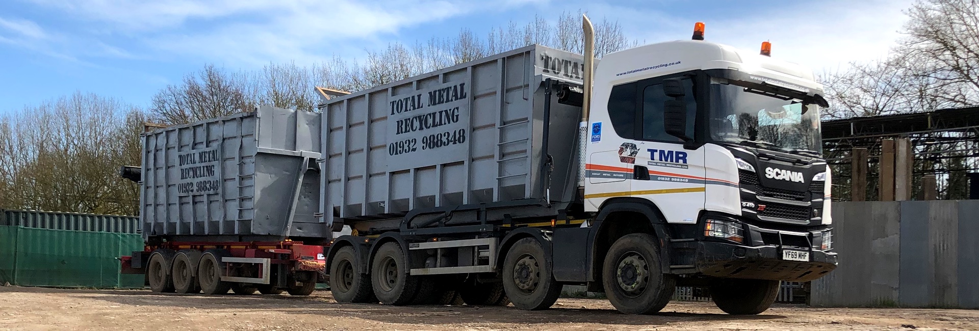 HGV with a roll on off bin on the back with Total Metal Recycling written on it.