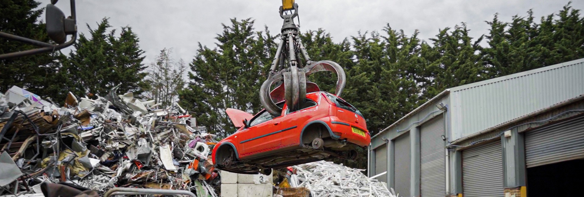 A red scrap car being lifted by a grabber for the ulez scrappage scheme