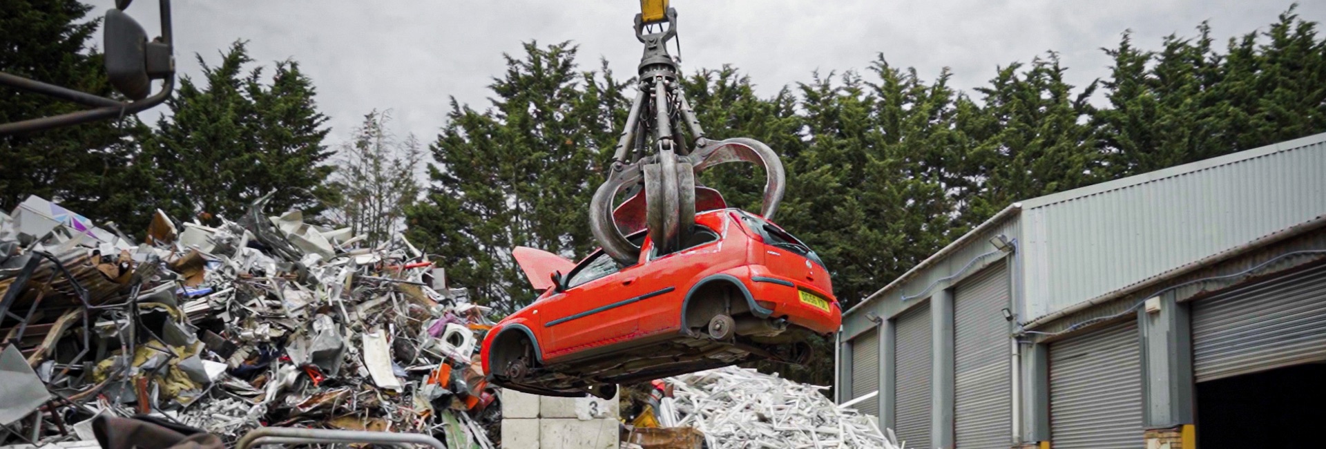 A scrap red car being lifted by a grabber for the ulez scrappage scheme