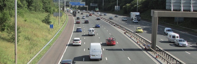 Multiple vehicles driving along a section of the M25 motorway in Surrey.